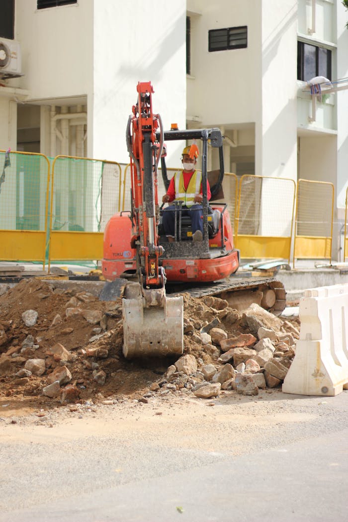 A construction worker operates a backhoe during a building project in an urban area.